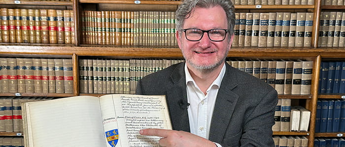 Archivist Gary Haines in the Law Society library pointing at a historical record.