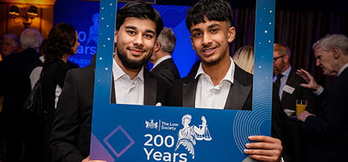 Two smiling men hold up a frame that says The Law Society 200 Years