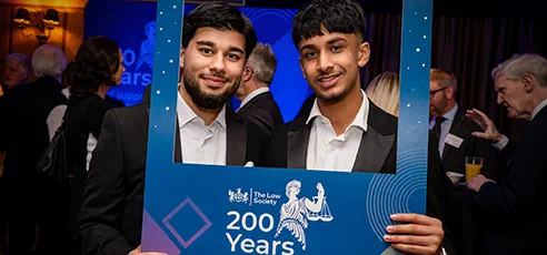 Two smiling men hold up a frame that says The Law Society 200 Years