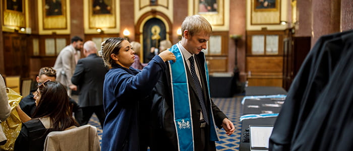 A solicitor is helped to put on a robe at a Law Society admission ceremony.