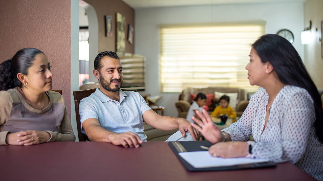 Asian couple meeting with solicitor at home, two children play in the background
