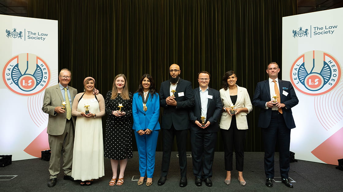 The 2023 Legal Heroes stand in a row with Lubna Shuja, president of the Law Society of England and Wales. Left to right: Clive Sutton, Shabina Begum, Emily McFadden, Lubna Shuja, Qaisar Sheikh, Martin Whitehorn, Sabeena Pirooz and Jonathan Lafferty.