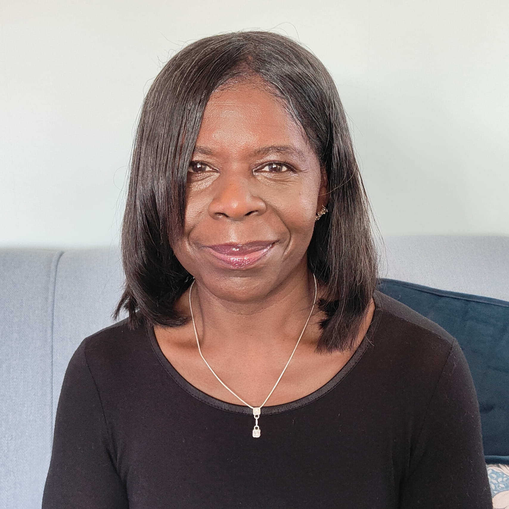 Pauline Campbell is a black woman with mid-length, straight black hair. She is smiling and wears a black t-shirt and a silver locket necklace.