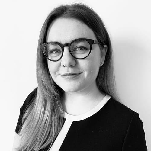Lizzie Hardy smiles, wearing a black and white dress.
