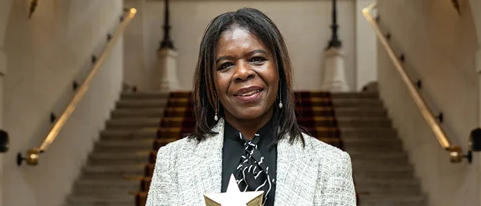 Legal Hero Pauline Campbell stands holding a star-shaped trophy.