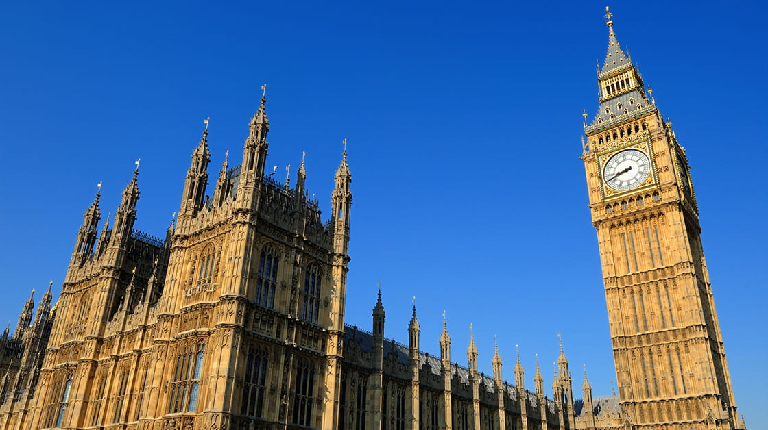 A view of the houses of parliament in Westminster from the ground, with a clear blue sky in the background.