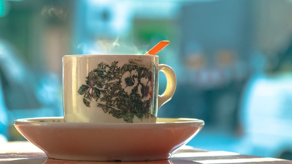 Steam rising from white and green ceramic mug on white ceramic plate 