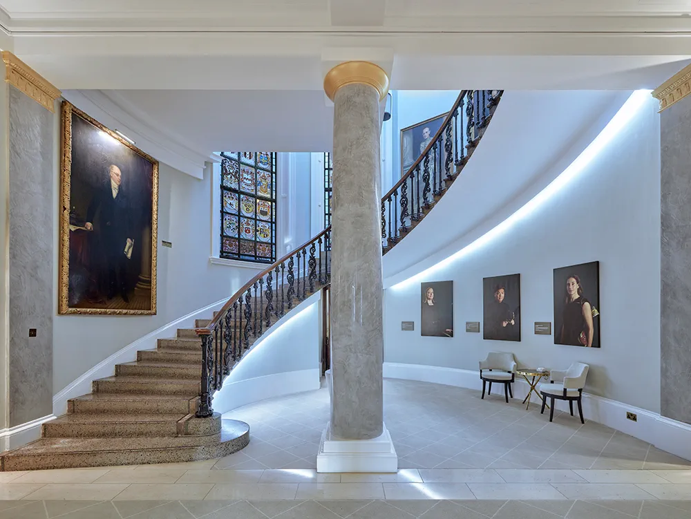 Ornate curved staircase leading to Law Society Library in 113 Chancery Lane: stained glass window and gold-framed portraits with central marble pillar