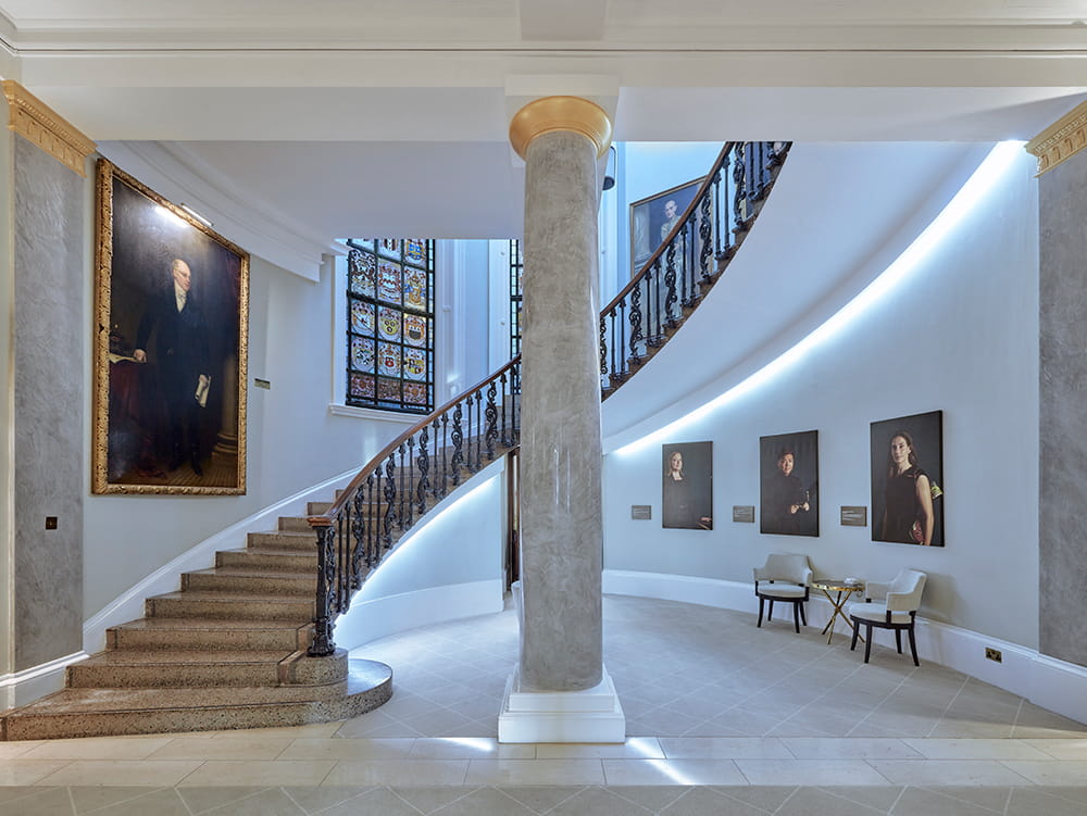 Ornate curved staircase leading to Law Society Library in 113 Chancery Lane: stained glass window and gold-framed portraits with central marble pillar
