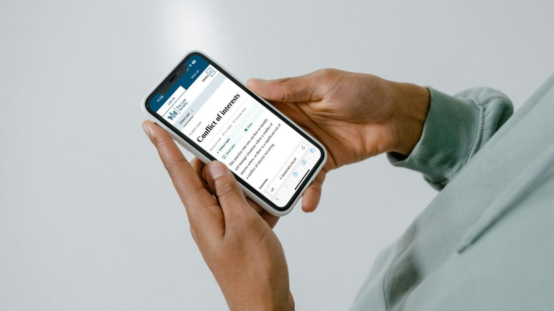 A person holding a mobile phone displaying our conflict of interests practice note.