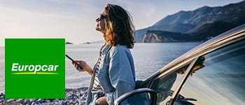 Europcar logo against a backdrop of a woman wearing sunglasses next to a vehicle.