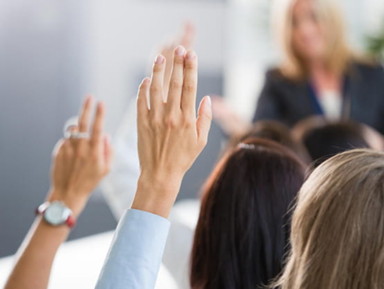 Professionals raise their hands in a business coaching session