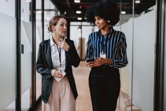 Two women speaking as they walk down a hallway
