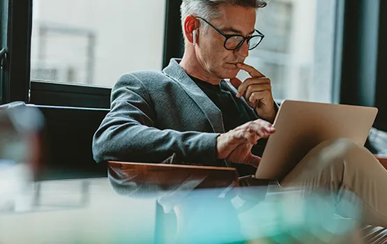 A man wearing glasses using a laptop.