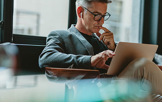 A man wearing glasses using a laptop.