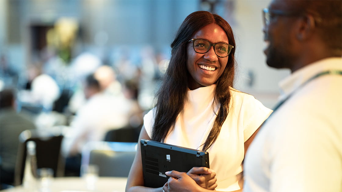 Two solicitors smile and talk at a conference.