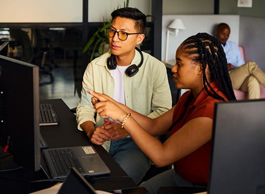 Two people work together at a computer in an office.