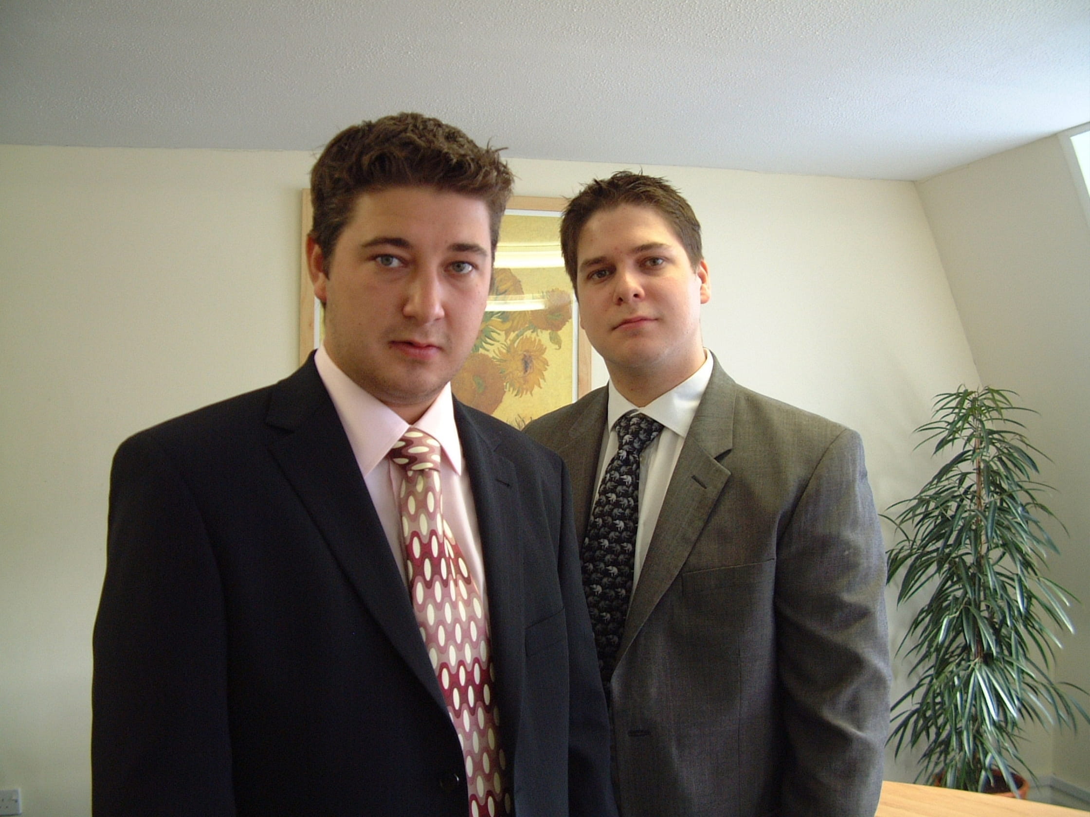 Two people wearing suits, standing.