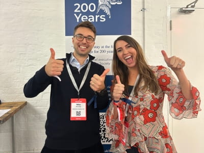 Sophie Jackson and Michael Kennedy at the Legal Geek conference smiling at the camera with their thumbs up.