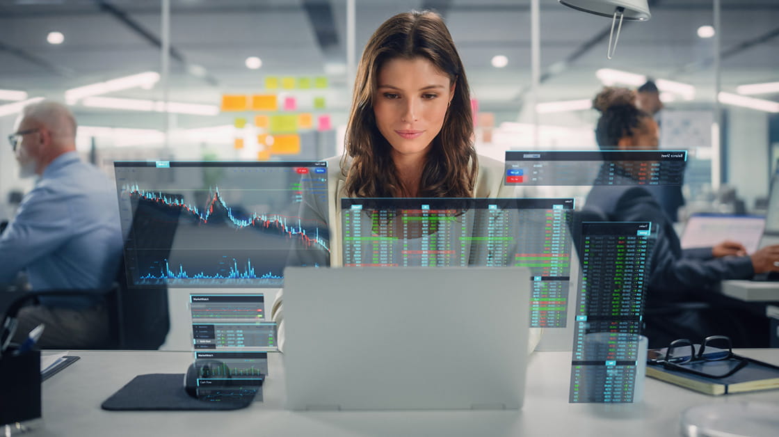 A woman with brown hair looks at her laptop in an office.