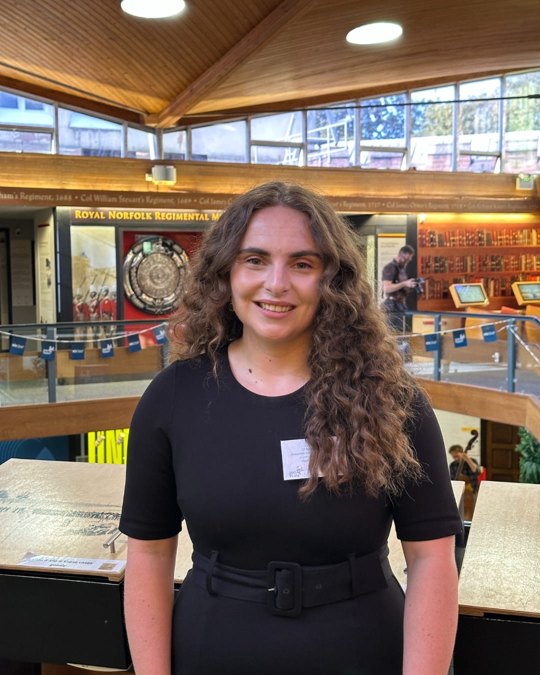 A woman in a black dress smiles at the camera.