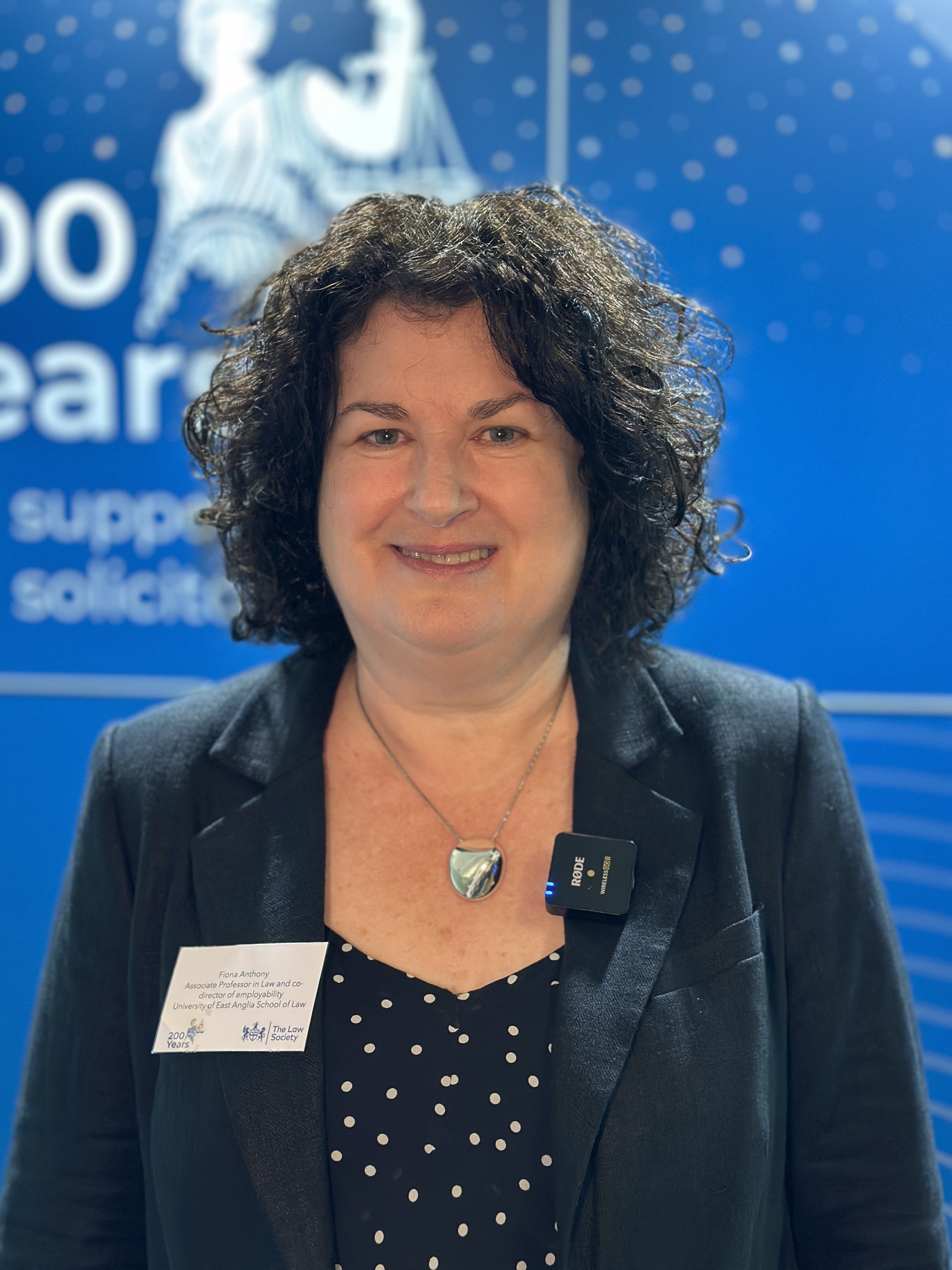 A woman in a blazer smiles. 