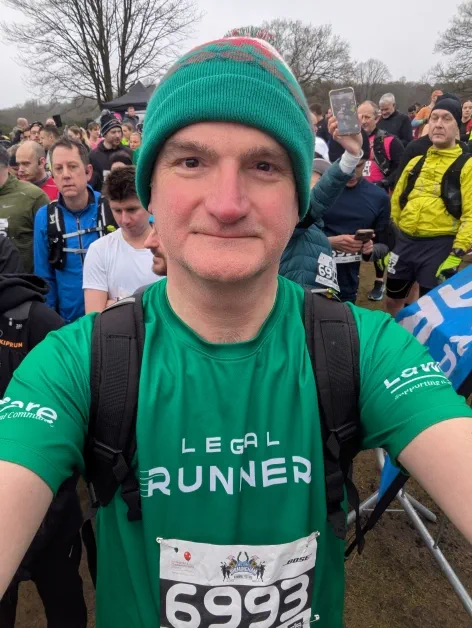 Runner in green athletic gear and beanie participating in an outdoor race.