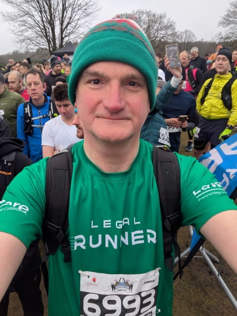 Runner in green athletic gear and beanie participating in an outdoor race.