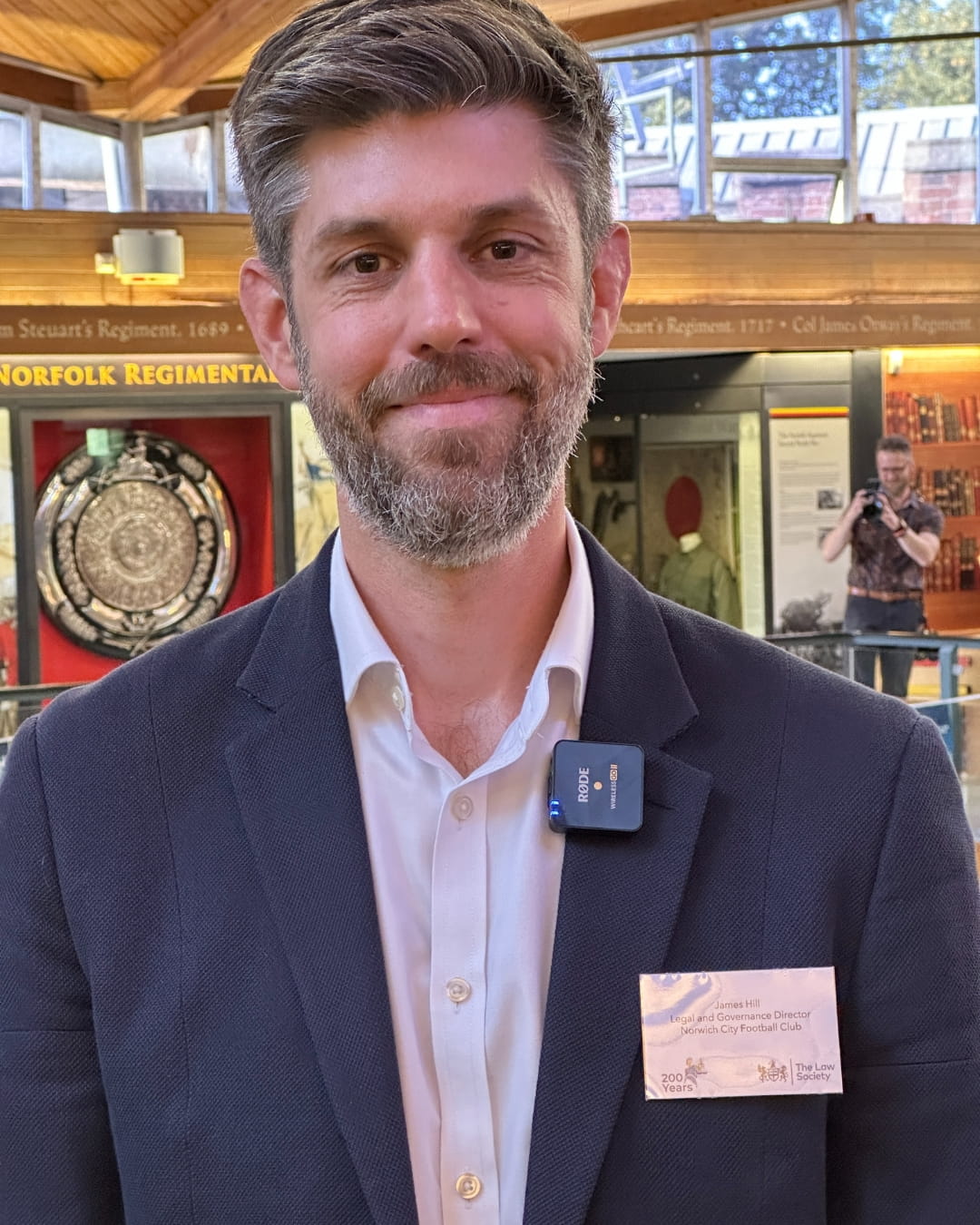 A man in a blazer smiles. 