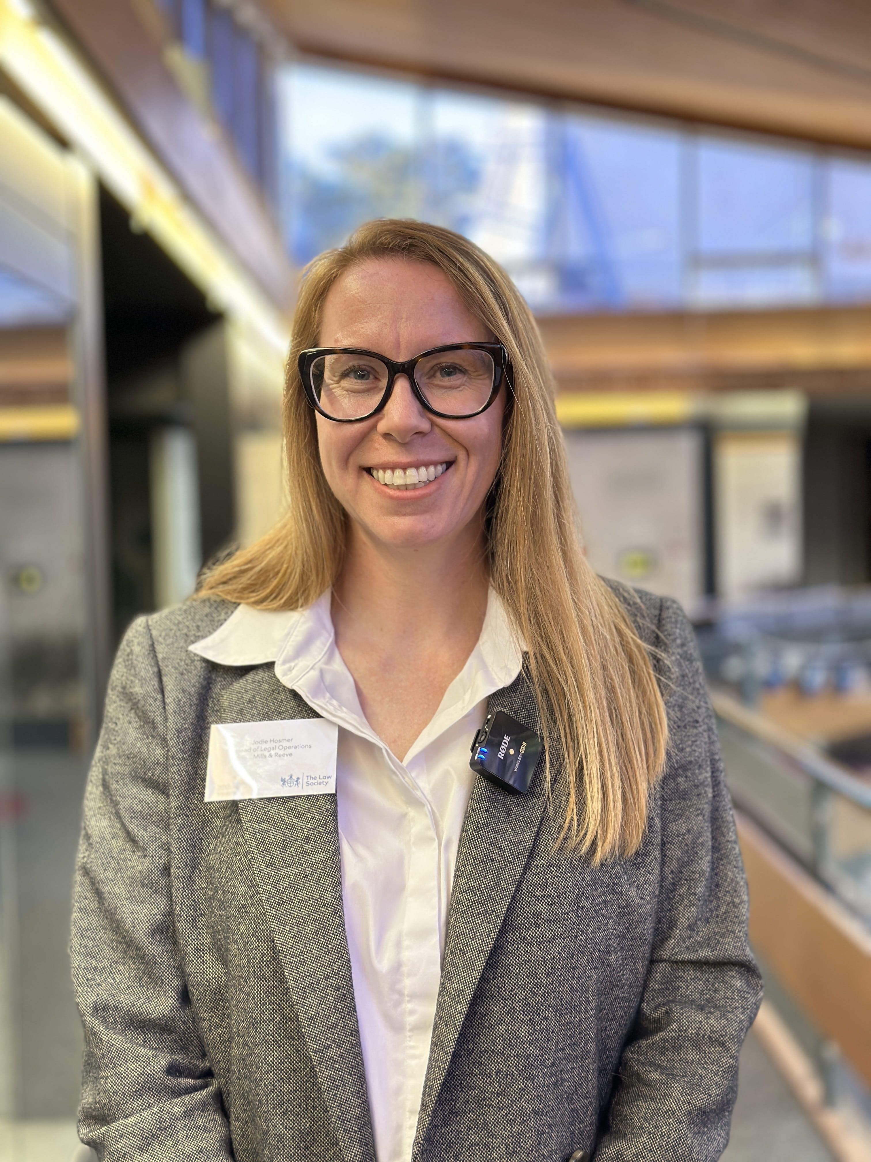 A woman with glasses smiles at the camera.