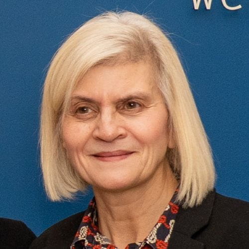 A woman with short blonde hair in a bob smiles 