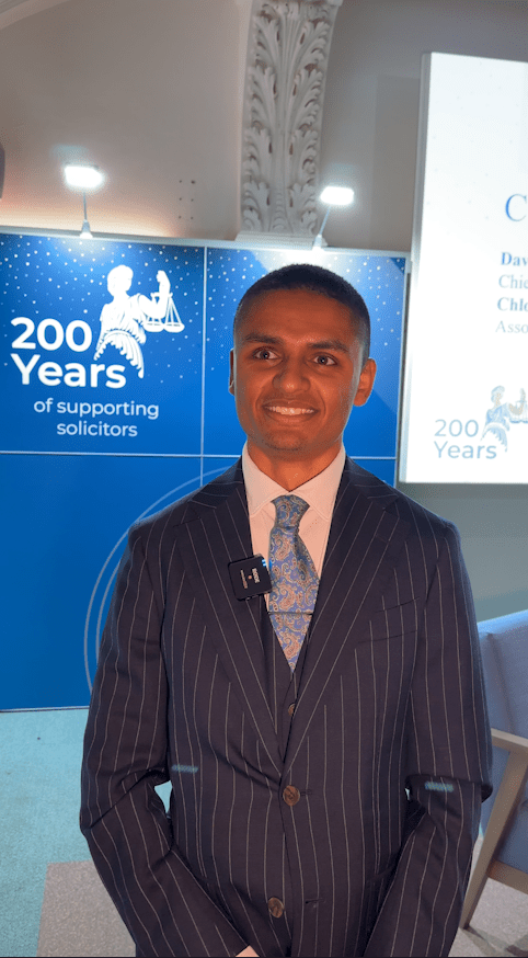 A man in a striped suit smiles at an event.