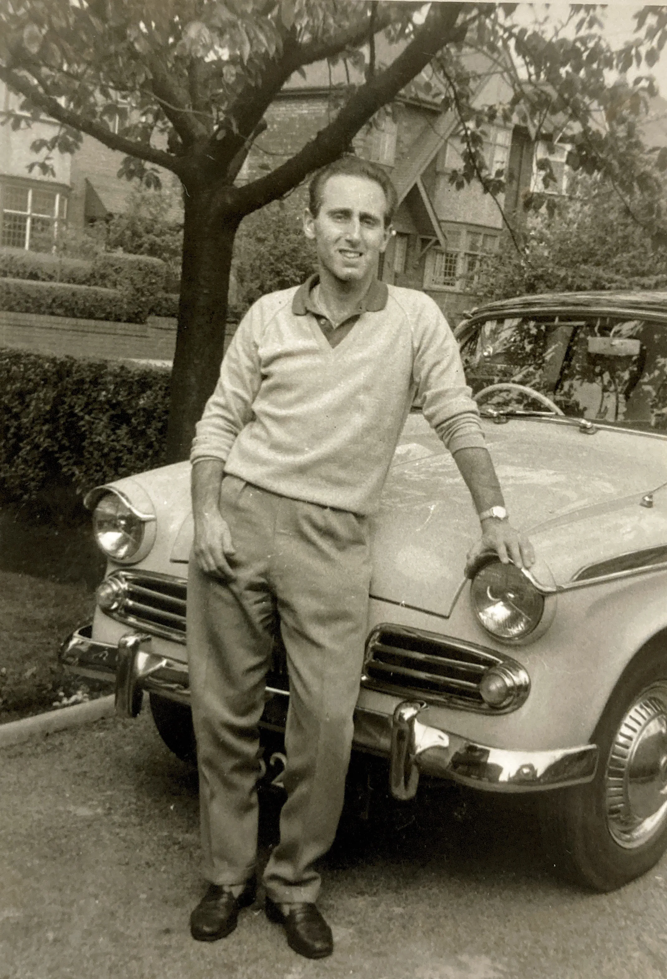 A man poses with a 1950s vintage car.