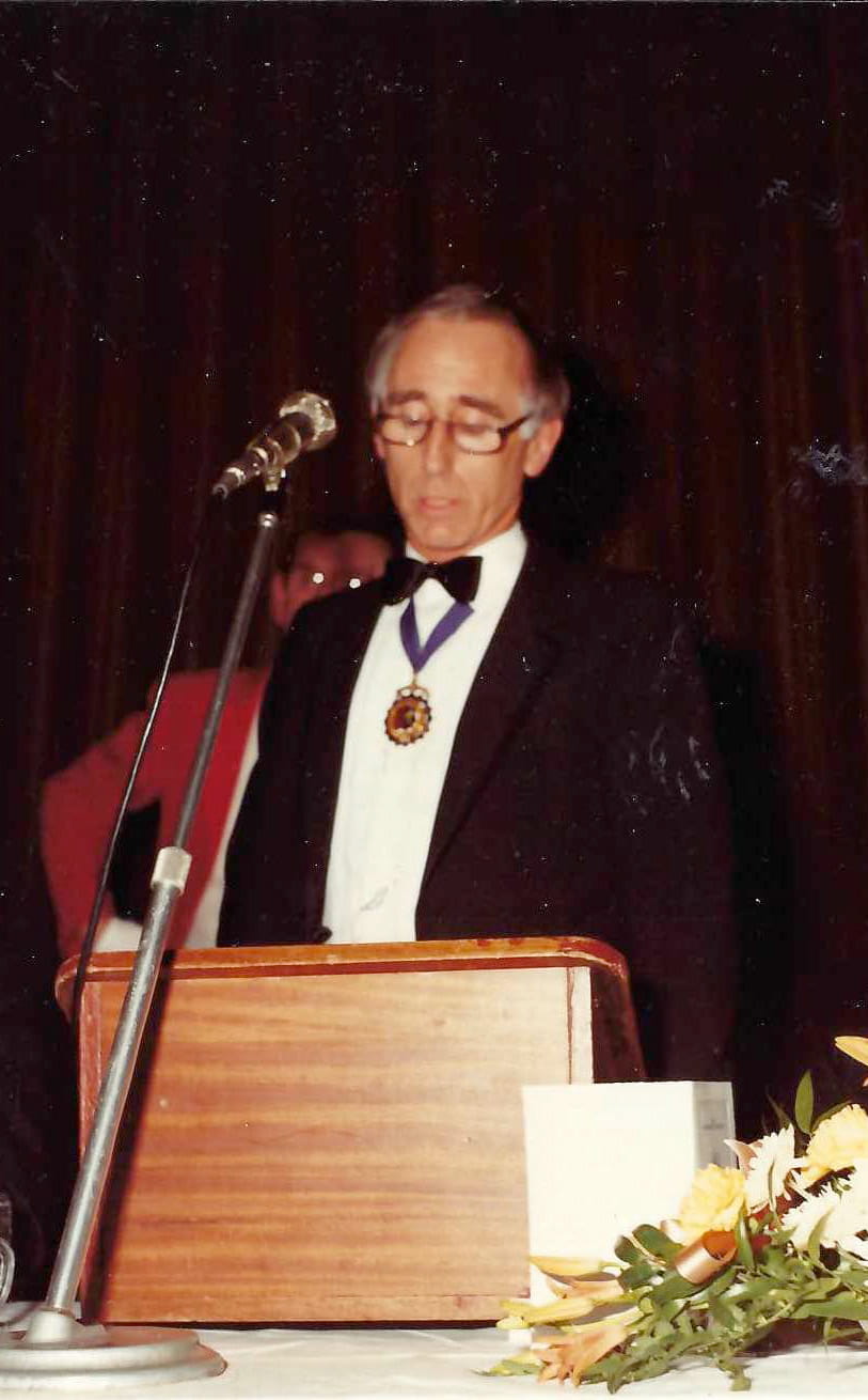 A man in formal attire makes a speech standing at a lectern