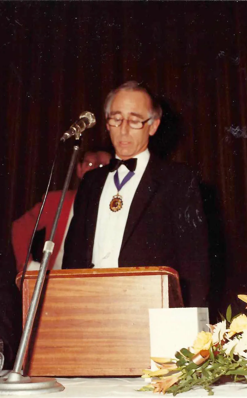 A man in formal attire makes a speech standing at a lectern