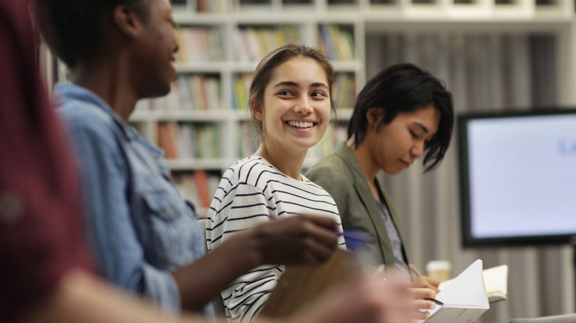 Young businesswoman sitting and smiling while talking to her colleagues during a seminar.