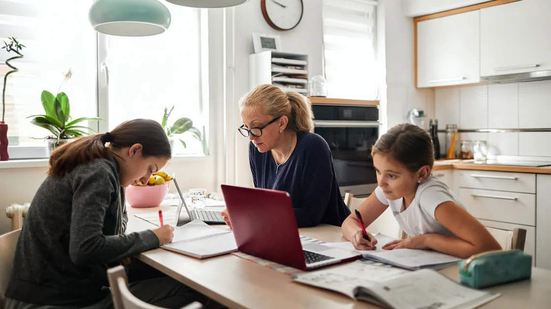 Parent working from home at table with children doing school work