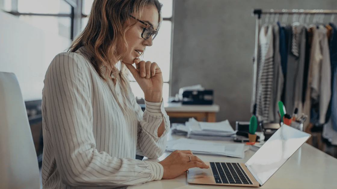 A woman sits at a desk using a laptop to work