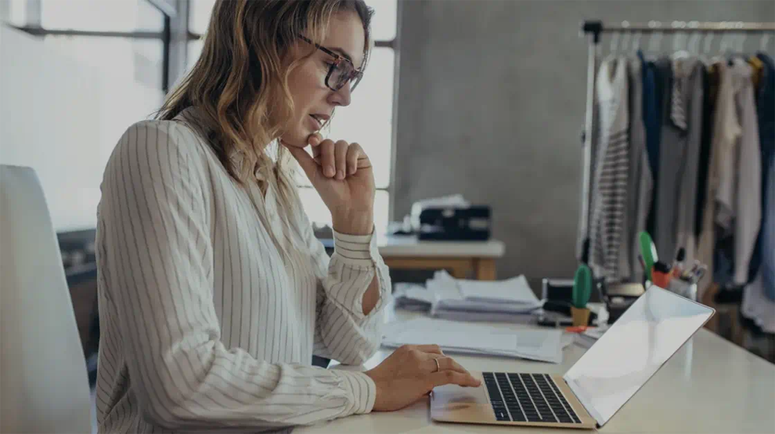 A woman sits at a desk using a laptop to work