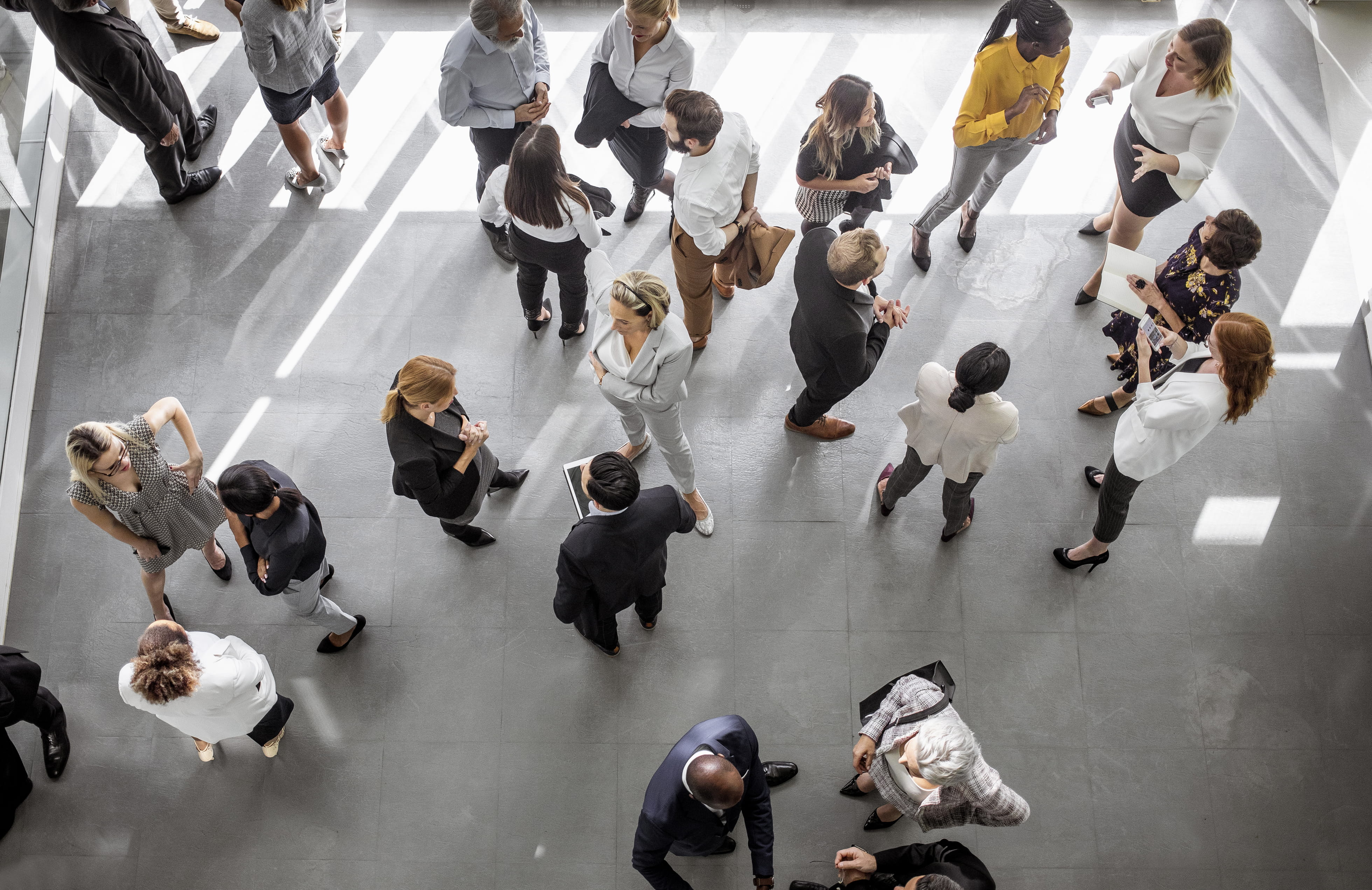 An aerial shot of group of people in business dress stand talking to one another.