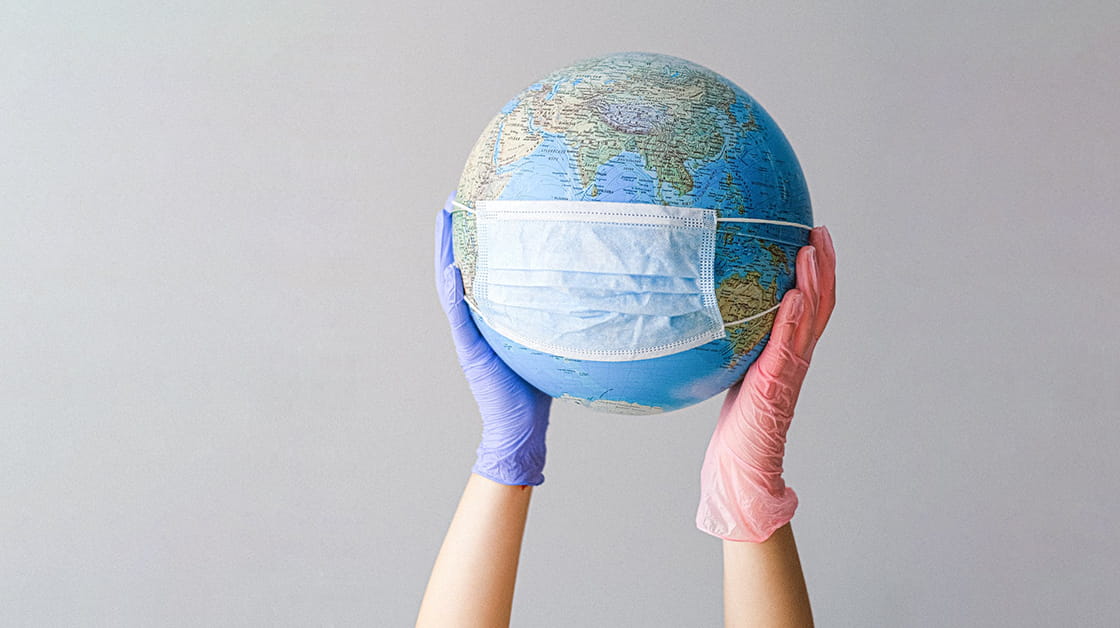 Hands with latex gloves holding a globe with a face mask