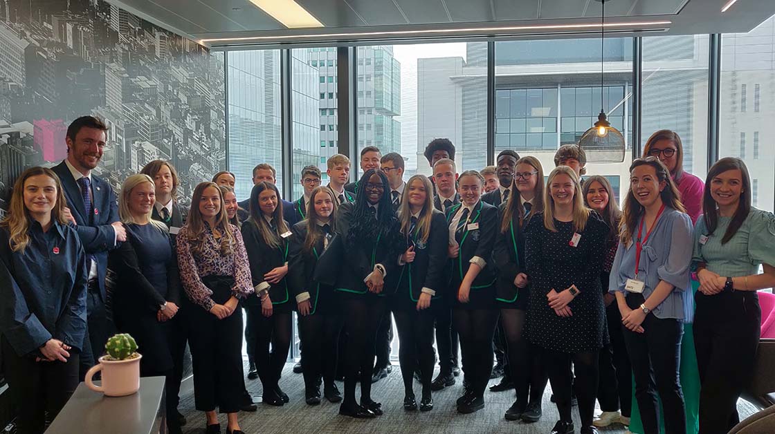 Group photo of class in school uniform with several adults in workwear wearing lanyards
