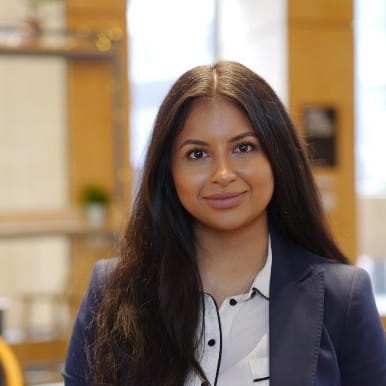 Shivani Jobanputra is an Asian woman in a white shirt and blue blazer, smiling at the camera