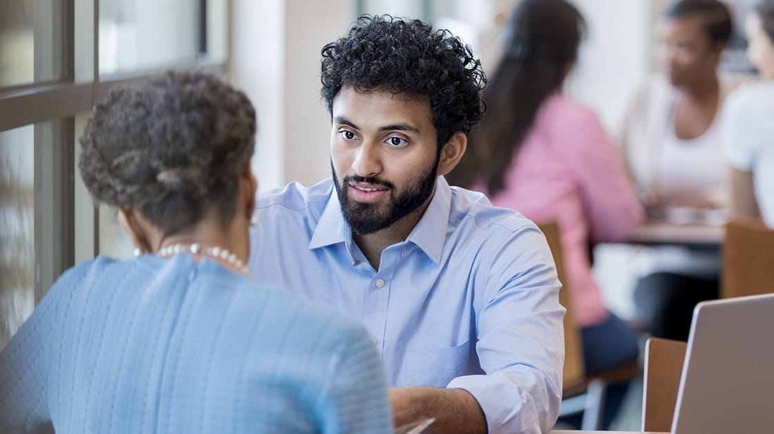 A junior colleague sits across the table from his mentor.