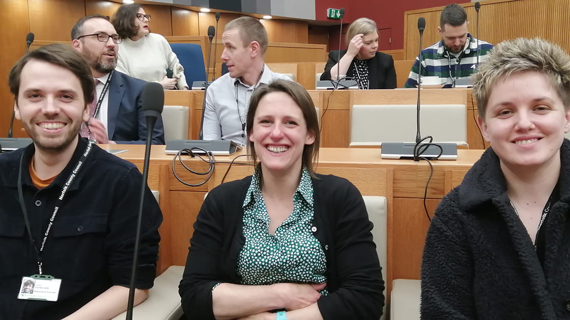 A man and two women in a lecture theatre.