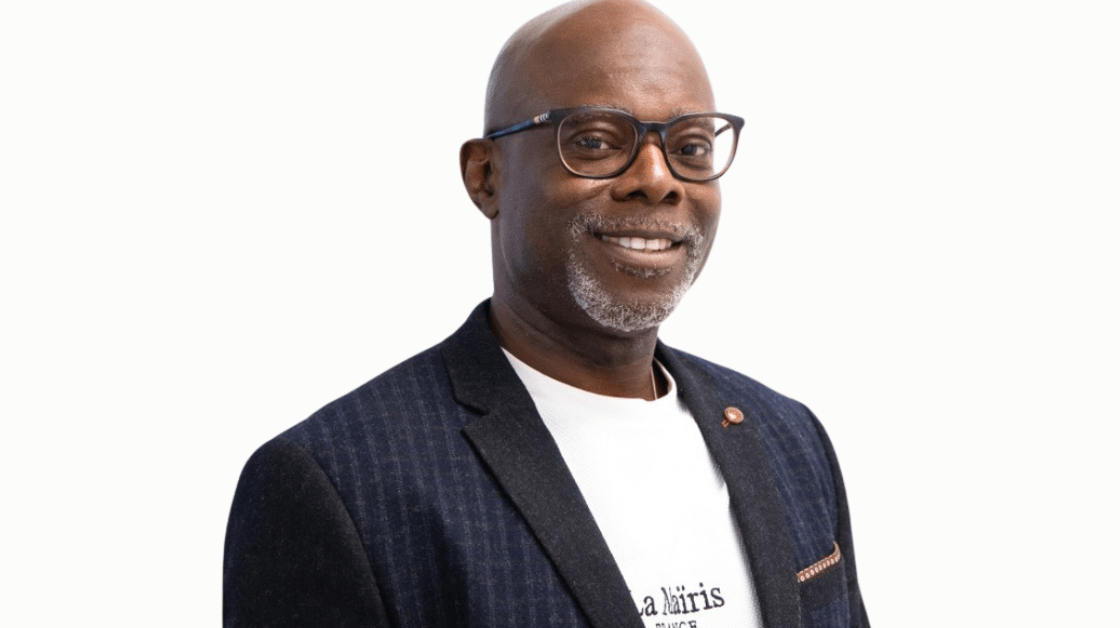 black man with dark rimmed glasses and beard wearing a checkered blazer