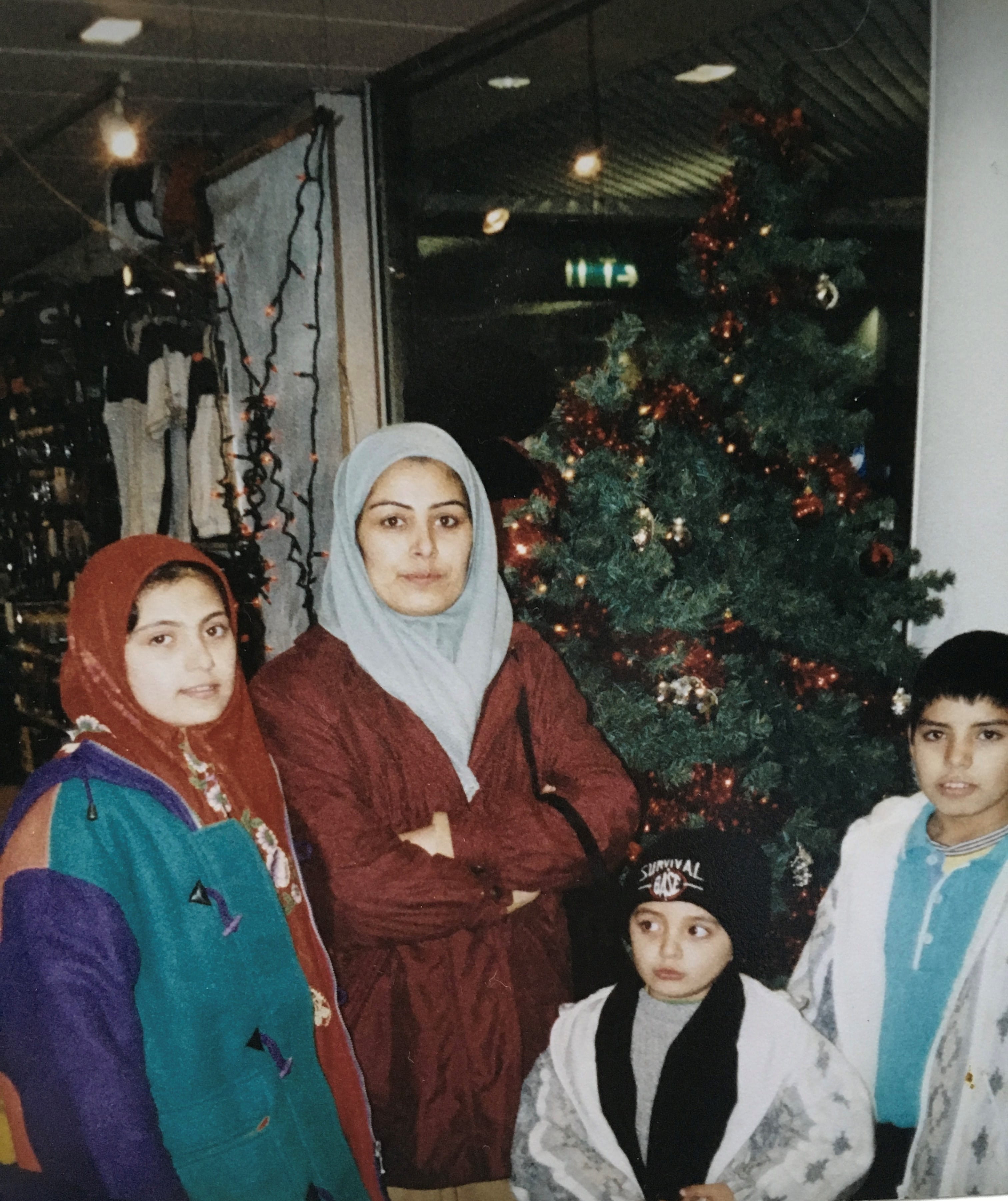 Qays with his family, standing in front of a Christmas tree.