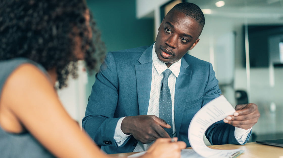 A man looks over documents with a female colleague.