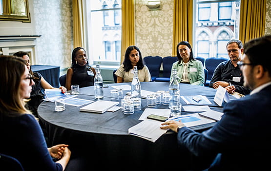 A group of in-house solicitors around a table in discussion at a forum.
