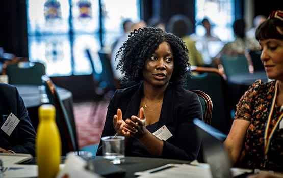An in-house solicitor talks with a group of colleagues around a table.